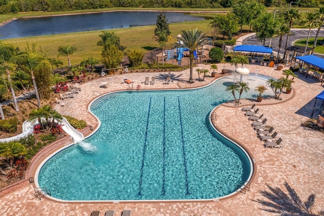 community pool featuring fence, a water slide, a water view, and a patio area