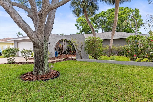 view of front of property with a front yard, concrete driveway, a garage, and stucco siding
