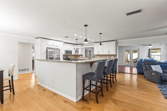 kitchen featuring stainless steel appliances, light wood-style floors, visible vents, and a breakfast bar area
