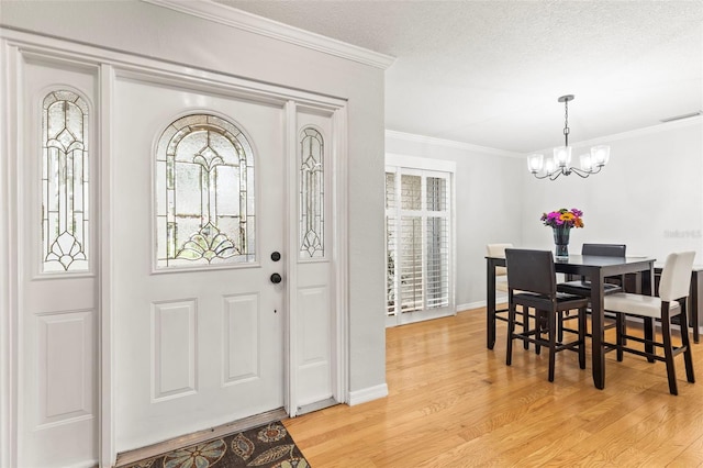 entryway featuring ornamental molding, a wealth of natural light, light wood finished floors, and an inviting chandelier