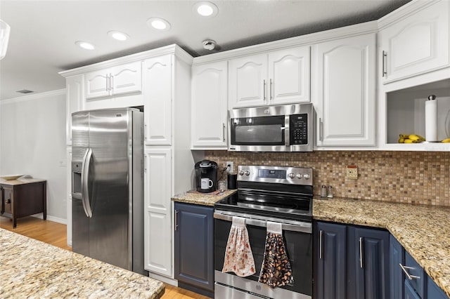 kitchen with white cabinets, blue cabinets, backsplash, and appliances with stainless steel finishes