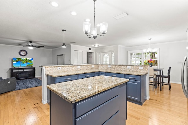 kitchen featuring tasteful backsplash, a center island, blue cabinets, and ceiling fan with notable chandelier