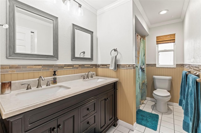 bathroom with tile patterned floors, toilet, a sink, and a wainscoted wall
