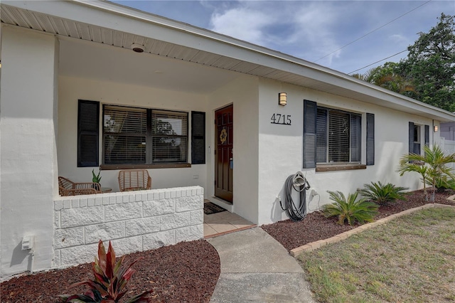property entrance featuring stucco siding and covered porch