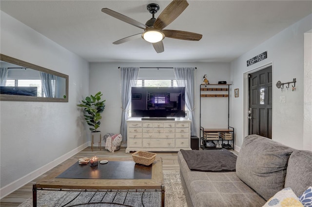 living room featuring baseboards, ceiling fan, and wood finished floors
