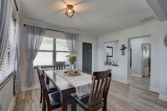 dining area with baseboards, visible vents, and wood finish floors
