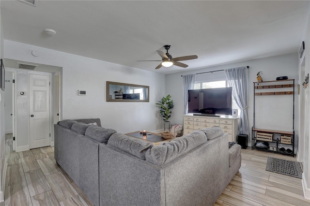 living room with wood tiled floor, ceiling fan, and visible vents