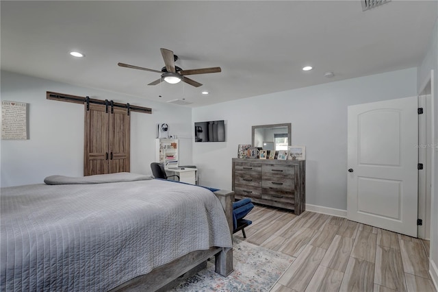 bedroom featuring light wood-type flooring, a barn door, ceiling fan, and recessed lighting