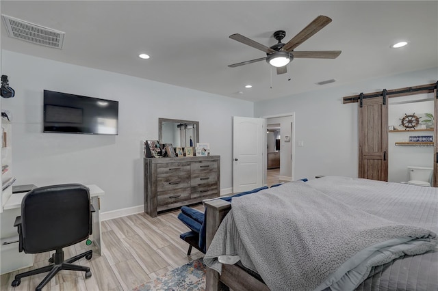 bedroom featuring a barn door, visible vents, recessed lighting, and light wood finished floors