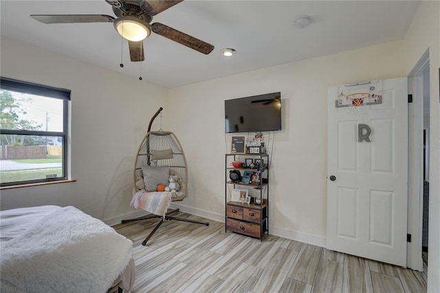 bedroom featuring baseboards, light wood-type flooring, and a ceiling fan