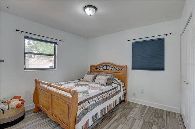 bedroom featuring light wood-style flooring, a closet, and baseboards
