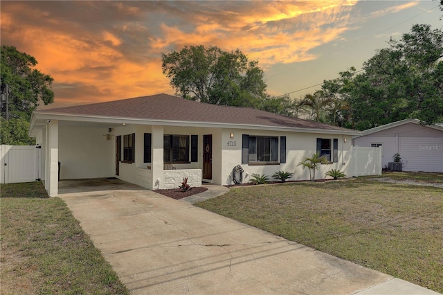 ranch-style house with a gate, a lawn, concrete driveway, an attached carport, and stucco siding
