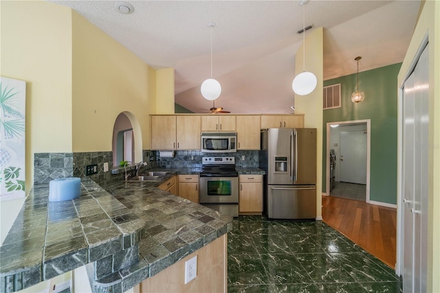 301 Caloosa Palms Ct, Sun City Center, FL 33573 - kitchen featuring appliances with stainless steel finishes, light brown cabinetry, tile counters, high vaulted ceiling, and a peninsula