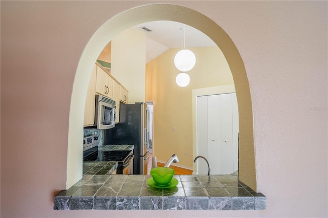 301 Caloosa Palms Ct, Sun City Center, FL 33573 - kitchen with appliances with stainless steel finishes, high vaulted ceiling, arched walkways, light brown cabinetry, and dark countertops