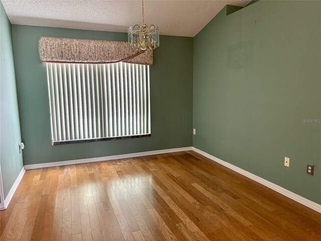 301 Caloosa Palms Ct, Sun City Center, FL 33573 - unfurnished room featuring a chandelier, wood finished floors, a textured ceiling, and plenty of natural light