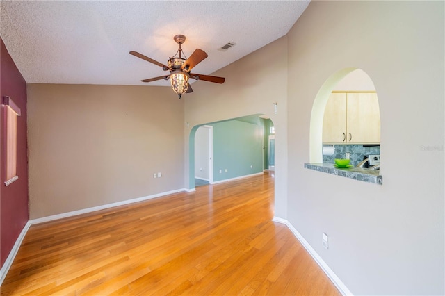 301 Caloosa Palms Ct, Sun City Center, FL 33573 - spare room with ceiling fan, light wood-type flooring, vaulted ceiling, arched walkways, and a textured ceiling
