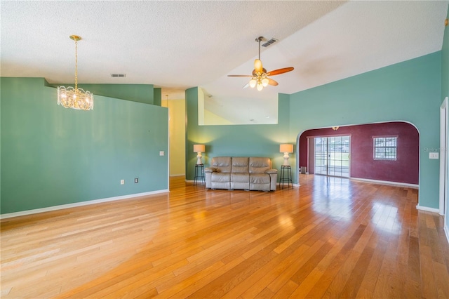 301 Caloosa Palms Ct, Sun City Center, FL 33573 - unfurnished living room featuring arched walkways, hardwood / wood-style floors, a ceiling fan, a chandelier, and a textured ceiling