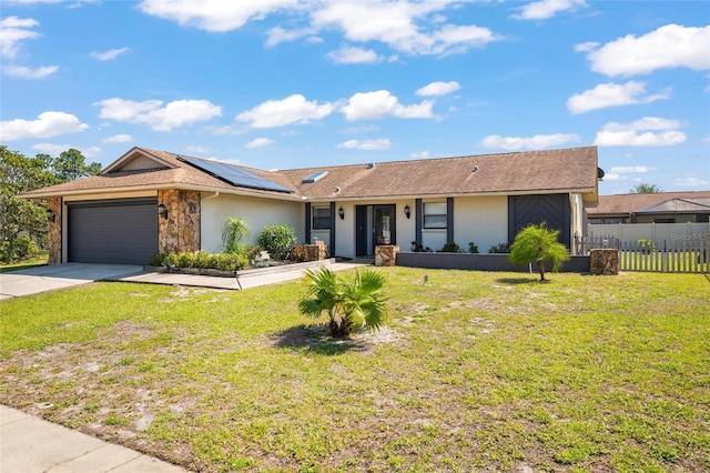 single story home featuring a front lawn, fence, an attached garage, and roof mounted solar panels