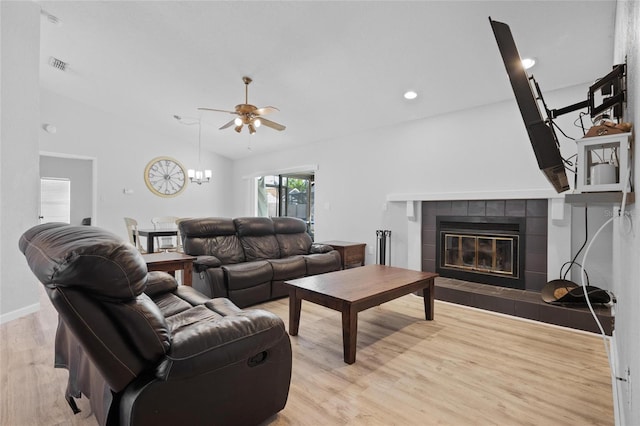 living room with visible vents, a ceiling fan, a fireplace, vaulted ceiling, and wood finished floors