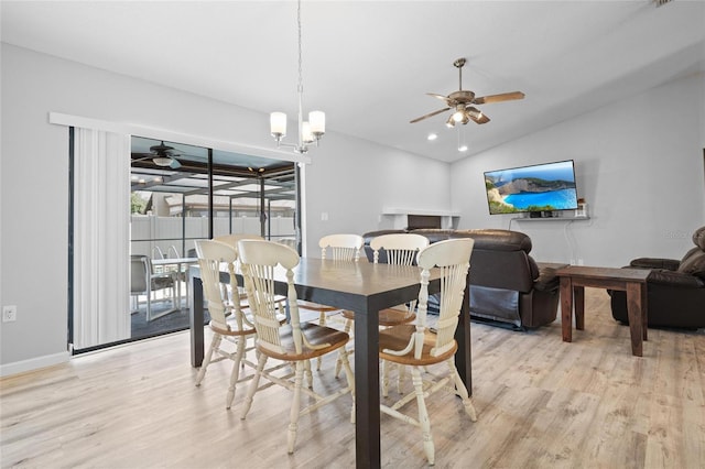 dining area with baseboards, vaulted ceiling, light wood-style floors, and ceiling fan with notable chandelier