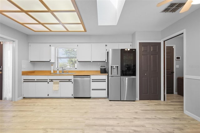 kitchen with white cabinets, visible vents, appliances with stainless steel finishes, light wood finished floors, and a sink