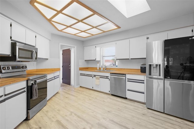 kitchen with butcher block counters, a skylight, decorative backsplash, and appliances with stainless steel finishes