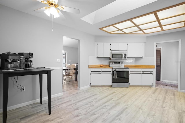 kitchen featuring ceiling fan, stainless steel electric stove, light wood-type flooring, white cabinetry, and decorative backsplash