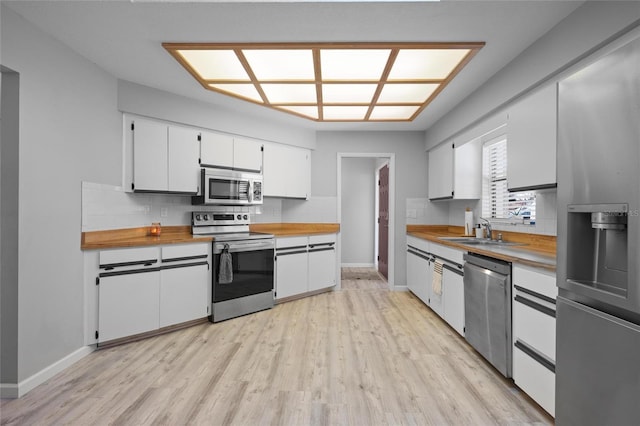kitchen with stainless steel appliances, wood counters, light wood-style flooring, and a sink