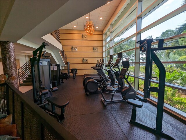 gym featuring a wealth of natural light, recessed lighting, wood walls, and a towering ceiling