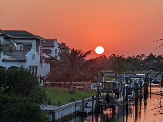 view of dock featuring a water view, fence, a yard, and boat lift