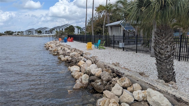 view of playground with a water view, fence, and a residential view