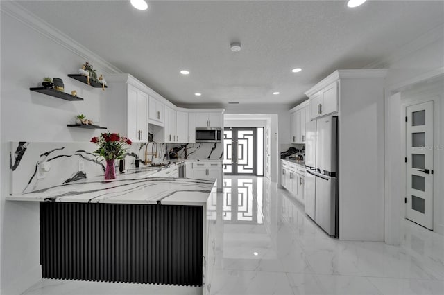 kitchen with white cabinets, a peninsula, marble finish floor, stainless steel microwave, and light stone counters
