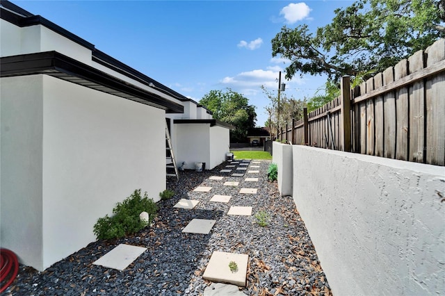 view of side of property featuring stucco siding and fence