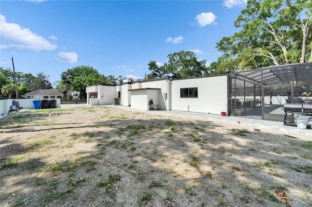 exterior space with stucco siding, fence, a patio, central air condition unit, and glass enclosure