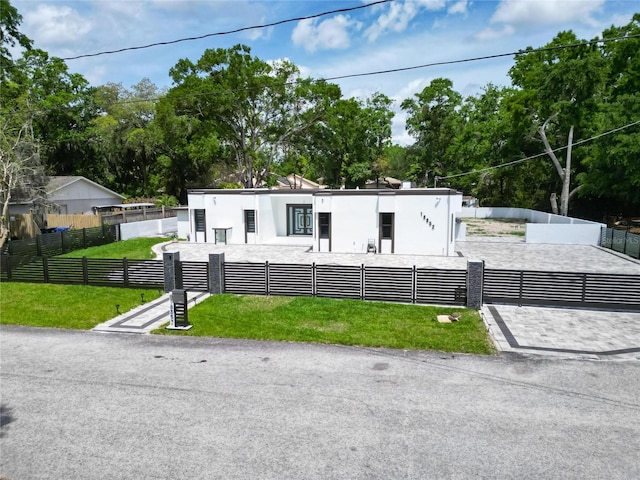 view of front of home with stucco siding, a front yard, and a fenced front yard