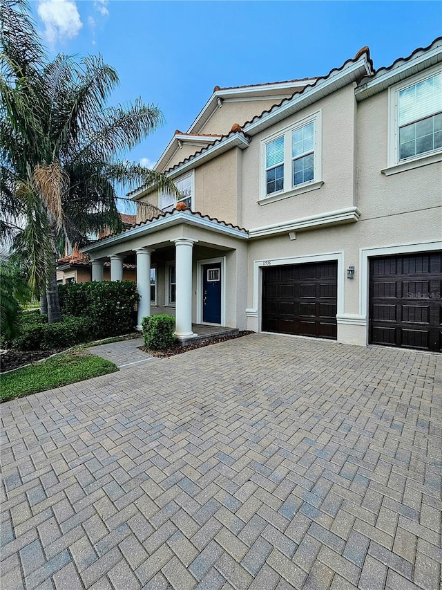 view of front of house featuring a tile roof, an attached garage, decorative driveway, and stucco siding