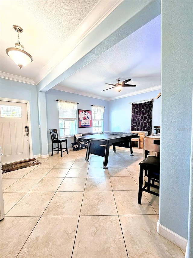 game room with baseboards, light tile patterned floors, a textured ceiling, crown molding, and a ceiling fan