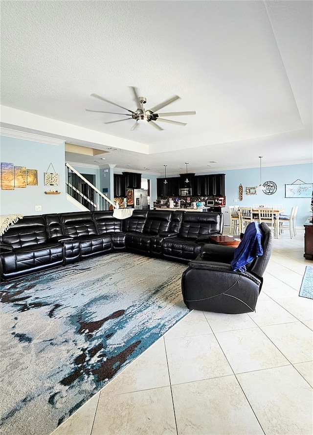 tiled living area featuring a tray ceiling, a ceiling fan, and a textured ceiling