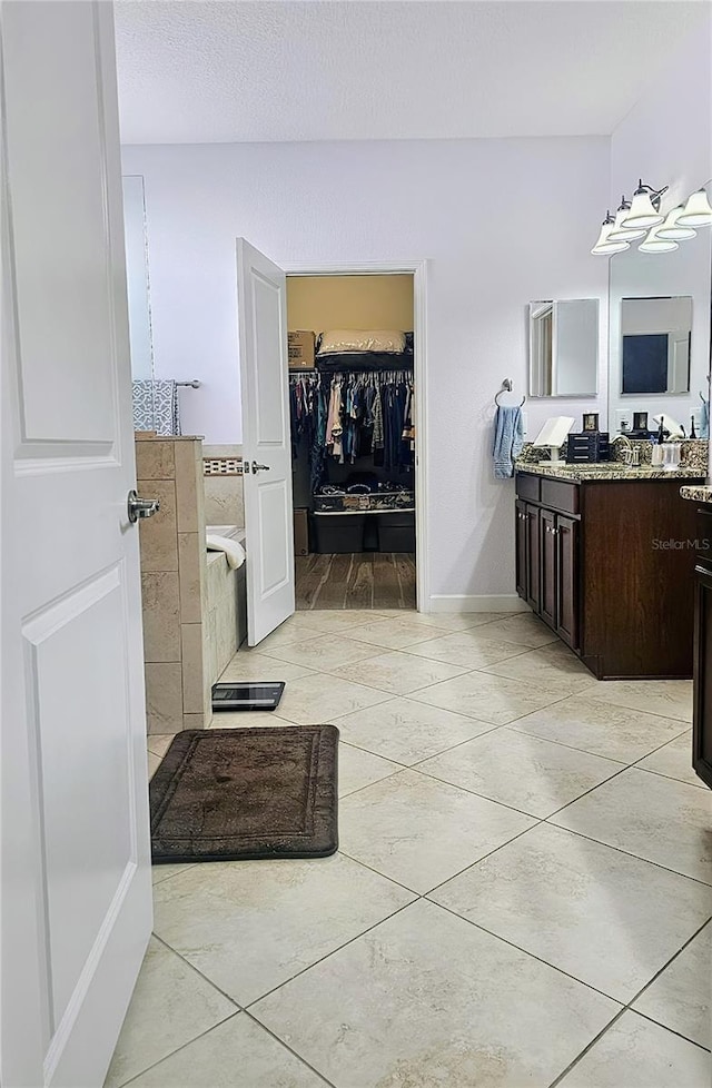 full bathroom featuring a spacious closet, tile patterned flooring, vanity, and baseboards