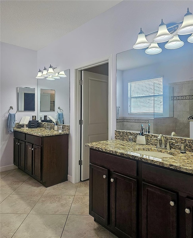 bathroom featuring a sink, two vanities, a walk in shower, and tile patterned flooring