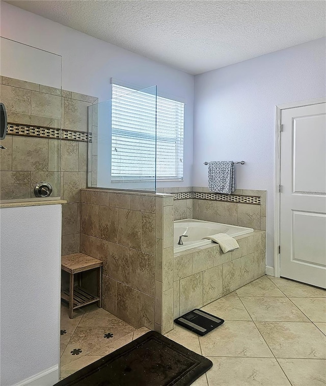 bathroom featuring tile patterned floors, a bath, a walk in shower, and a textured ceiling