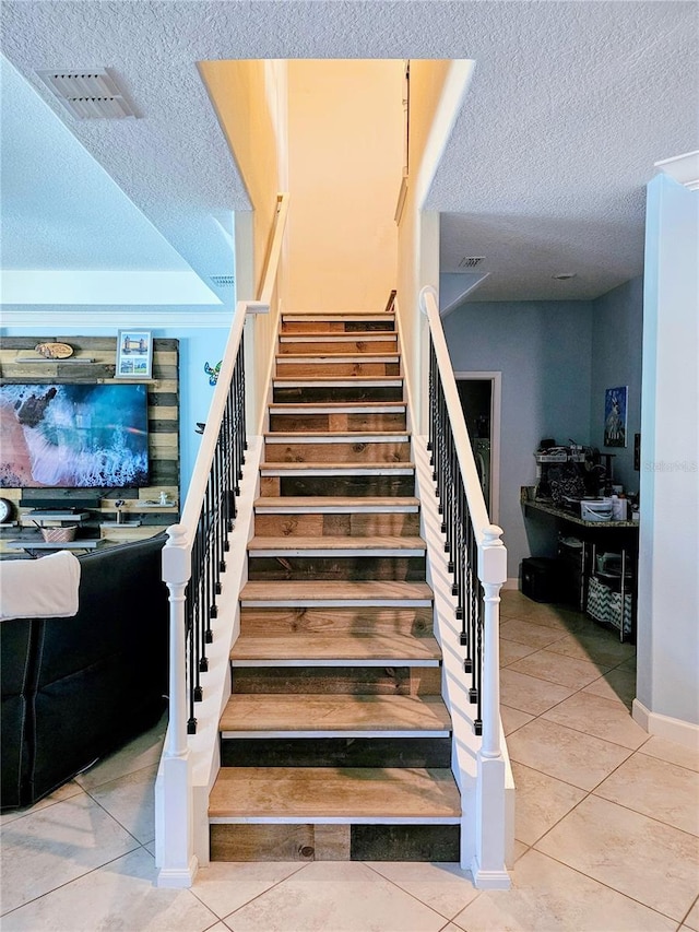 stairs featuring visible vents, tile patterned floors, and a textured ceiling