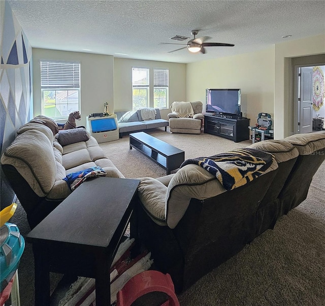 living area featuring a textured ceiling, carpet flooring, a ceiling fan, and visible vents