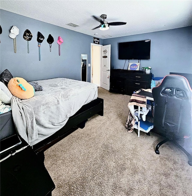carpeted bedroom featuring a textured ceiling, a ceiling fan, and visible vents