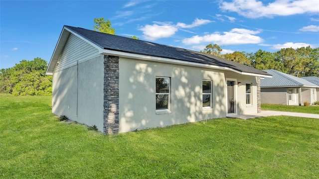 view of side of property featuring stucco siding, stone siding, and a lawn