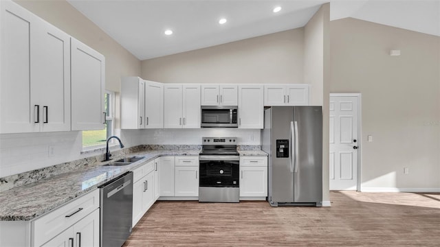 kitchen featuring white cabinetry, light wood-type flooring, stainless steel appliances, a sink, and light stone counters