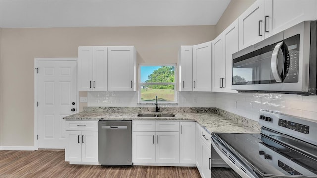 kitchen with light stone counters, a sink, light wood finished floors, white cabinetry, and appliances with stainless steel finishes