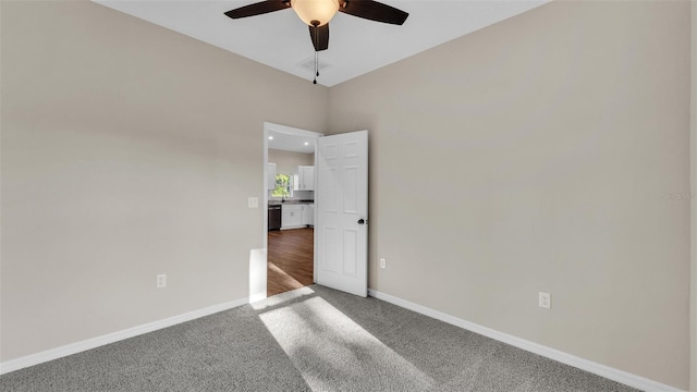 carpeted empty room featuring baseboards, visible vents, and a ceiling fan