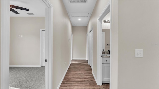 hallway with dark carpet, baseboards, and visible vents