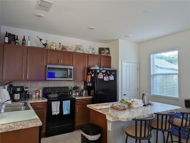 11527 Southern Creek Dr, Gibsonton, FL 33534 - kitchen with black appliances, light countertops, a kitchen breakfast bar, and a sink